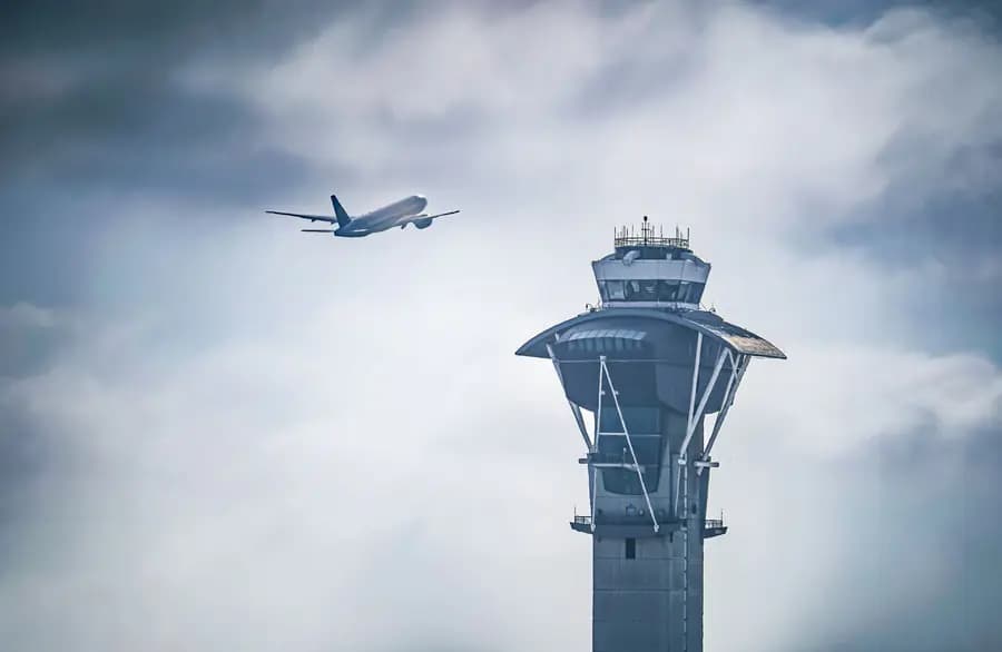 Passenger aircraft climbing past an airport control tower